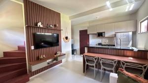 a living room with a television and a kitchen at Chalet Paraíso Lençóis Santo Amaro in Santo Amaro