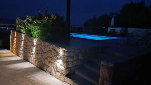 eine Steinmauer mit Lichtern neben einem Swimmingpool in der Unterkunft Apartments in Cizici - Insel Krk 31083 in Čižići