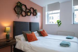 two beds in a bedroom with two windows at 1-Bed Apartment in Bournemouth centre in Bournemouth