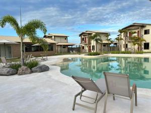 a swimming pool with a chair and some houses at Chalet Paraíso Lençóis Santo Amaro in Santo Amaro