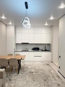 una cucina con un tavolo in legno e mobili bianchi di Роскошная двухкомнатная квартира a Almaty