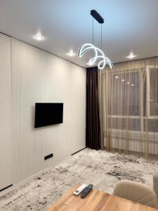 un soggiorno con un tavolo e una TV a parete di Роскошная двухкомнатная квартира a Almaty Altre 3 foto