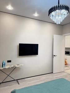 un soggiorno con TV su una parete bianca di Роскошная двухкомнатная квартира a Almaty