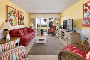 ein Wohnzimmer mit einem roten Sofa und einem TV in der Unterkunft Beach Club #111 in Saint Simons Island