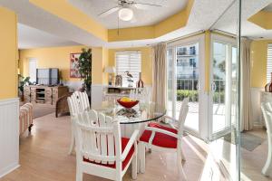 ein Esszimmer mit einem Glastisch und weißen Stühlen in der Unterkunft Beach Club #111 in Saint Simons Island