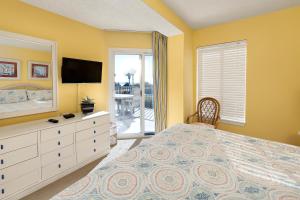 ein Schlafzimmer mit einem Bett und einer Kommode mit einem Fernseher in der Unterkunft Beach Club #111 in Saint Simons Island + 30 Fotos