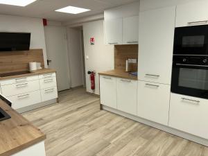 an empty kitchen with white cabinets and black appliances at Grande maison, jusqu’à 14 personnes, calme entre forêt et montagne - FR-1-744-47 in Hohrod +27 photos