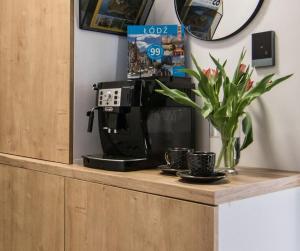 eine Theke mit Kaffeemaschine und eine Vase mit Pflanze in der Unterkunft Tucan - 77 Apartments Wigury - Dostęp na KOD - Parking - Smaczna Kawa - Centrum - Blisko Piotrkowska - Galeria - Widok na miasto - Klimatyzacja - 7 piętro - FV in Łódź