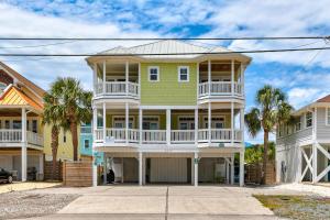 a yellow and white house with palm trees at The Pelican in Carolina Beach