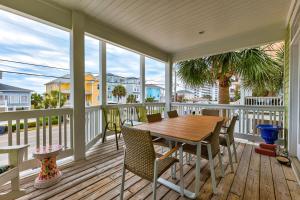 a porch with a wooden table and chairs at The Pelican in Carolina Beach