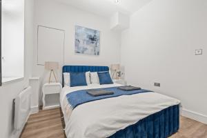 a white bedroom with a blue and white bed at Cardiff Luxe Flats with Spa Facilities in Cardiff