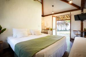a bedroom with a large white bed and a sliding glass door at VELINN Pousada Bromelias in Ilhabela +36 photos