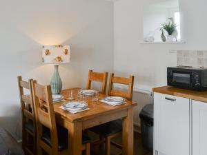 a kitchen with a wooden table with chairs and a microwave at Heron Cottage in Alnham