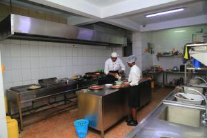 two chefs standing in a kitchen preparing food at Alma Hotel, Kitengela in Nairobi