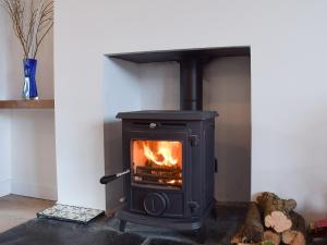 a black stove with a fire in a room at Glasfor in Llanon