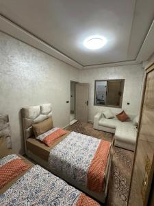 a room with two beds and a couch at شقة مفروشة للكراء اكادير للعائلات فقط in Agadir