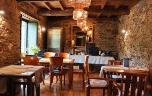restauracja ze stołami i krzesłami oraz kamienną ścianą w obiekcie Fogar de Lecer w mieście Arzúa