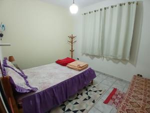 サン・ベント・ド・サプカイーにあるCasa Descanso São Bento Sapucaíのベッドルーム1室(紫のシーツが敷かれたベッド1台、窓付)