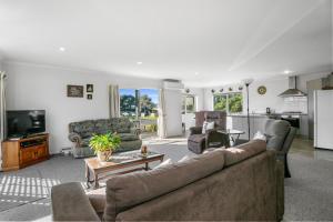 a living room with a couch and a tv at Golden Dawn in Waihi Beach