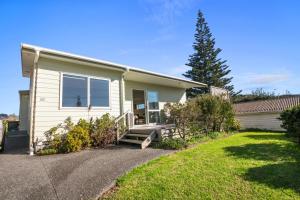 a house with a bench in front of a yard at Golden Dawn in Waihi Beach