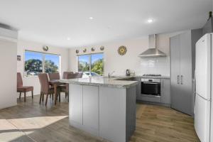 a kitchen with white cabinets and a table with chairs at Golden Dawn in Waihi Beach