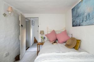 a bedroom with a bed with pink pillows on it at Tudor Rose Cottage in Stourpaine