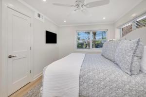 Un dormitorio blanco con una cama y un ventilador de techo. en 588 Demere-2, en Saint Simons Island