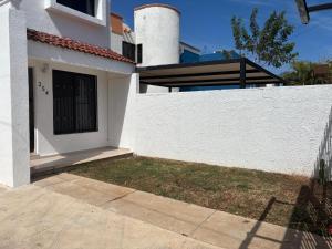 a white house with a fence and a yard at CASA COLIBRÍ - Solo Mujeres! & lgbt friendly in Mérida
