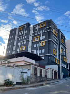 a tall black building with yellow windows on a street at Absolut Residense in João Monlevade