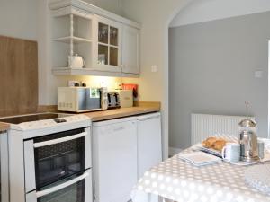 a small kitchen with white appliances and a table at The Old School House Cottage in Coupar Angus