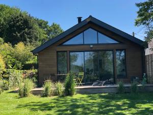 a cottage with large glass doors in a garden at Petit coin paisible entre terre et mer in Plescop
