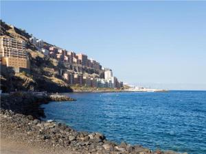 a beach with buildings on a hill next to the water at Live Tabaiba Maritime in Tabaiba