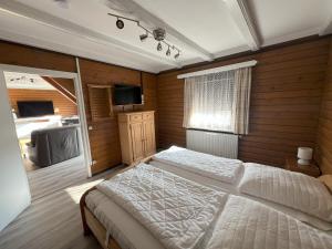 a bedroom with a white bed and a television at Haus 44 Feldblick Fewo 1 oben in Arrach