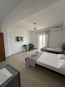 a white bedroom with two beds and a dining room at Kolagji Rooms in Lukovë