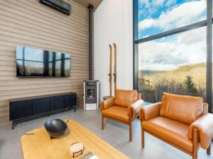 サセックスにあるLuxury Cabin with Private Hot Tub Minutes from Poley Mountain & Sussexの椅子2脚とテレビのあるリビングルーム