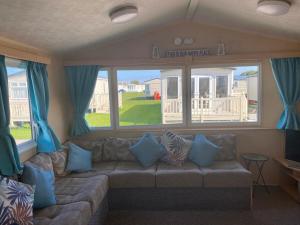 a living room with a couch with blue pillows at The Retreat Palm - Lido Beach in Prestatyn