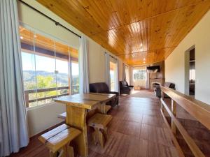 a room with a wooden table and some windows at Chácara das Palmeiras - 16 min do Capivari in Campos do Jordão +46 photos