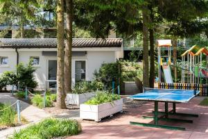 a ping pong table in a park with a playground at Wojtek - domki letniskowe i pokoje, animacje, melex na plażę in Dziwnów