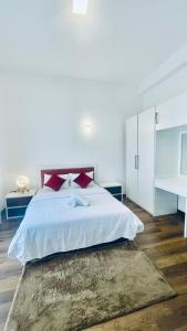 Un dormitorio blanco con una cama grande con almohadas rojas. en THE - CR7 - Manchester Grand apartment, en Nuwara Eliya