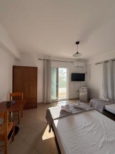 a bedroom with a bed and a table and a television at Kolagji Rooms in Lukovë