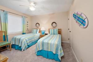 a bedroom with two beds and a ceiling fan at Beach Club #118 in Saint Simons Island +29 photos