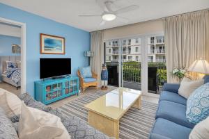 a living room with a couch and a tv at Beach Club #127 in Saint Simons Island