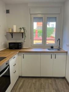 a kitchen with white cabinets and a sink and a window at Apartamento Solpor in A Guarda +10 photos