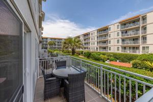 a balcony with a table and chairs and a building at Beach Club #127 in Saint Simons Island