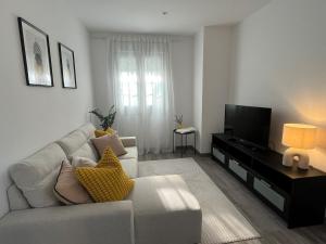 a living room with a white couch and a television at Apartamento Solpor in A Guarda