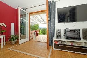 a living room with a television and a sliding glass door at Fill's Oase am Bach in Unterwössen