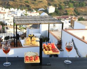 a table with two glasses of wine and food at Casa Maroma in Cómpeta +24 photos