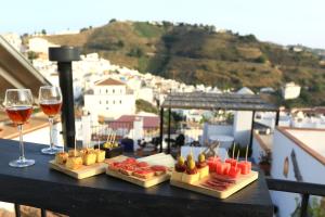 a table with wine glasses and food on a balcony at Casa Maroma in Cómpeta