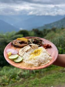 a person holding a plate of food with rice and vegetables at Homestay Ramdhura Heights in Pedong