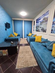 uma sala de estar com sofás azuis e almofadas amarelas em Elabd Family Porto Chalet em Marsa Matruh